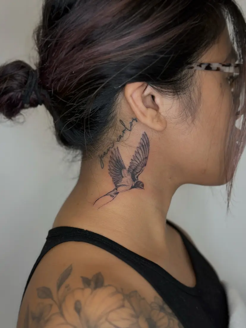 Fine-line swallow and script tattoo on the side of the neck