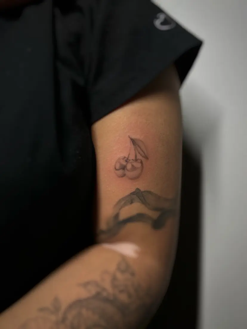 Small cherries tattoo on an upper arm