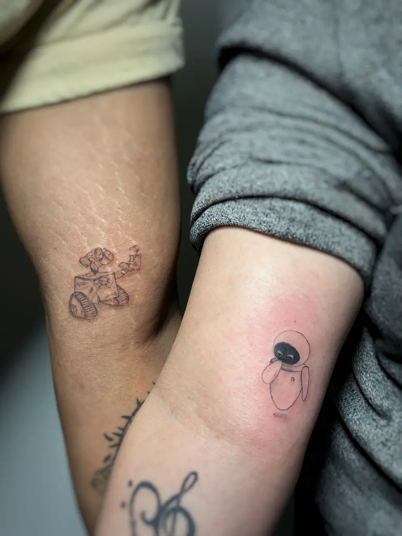 Matching small robot tattoos on two people's arms