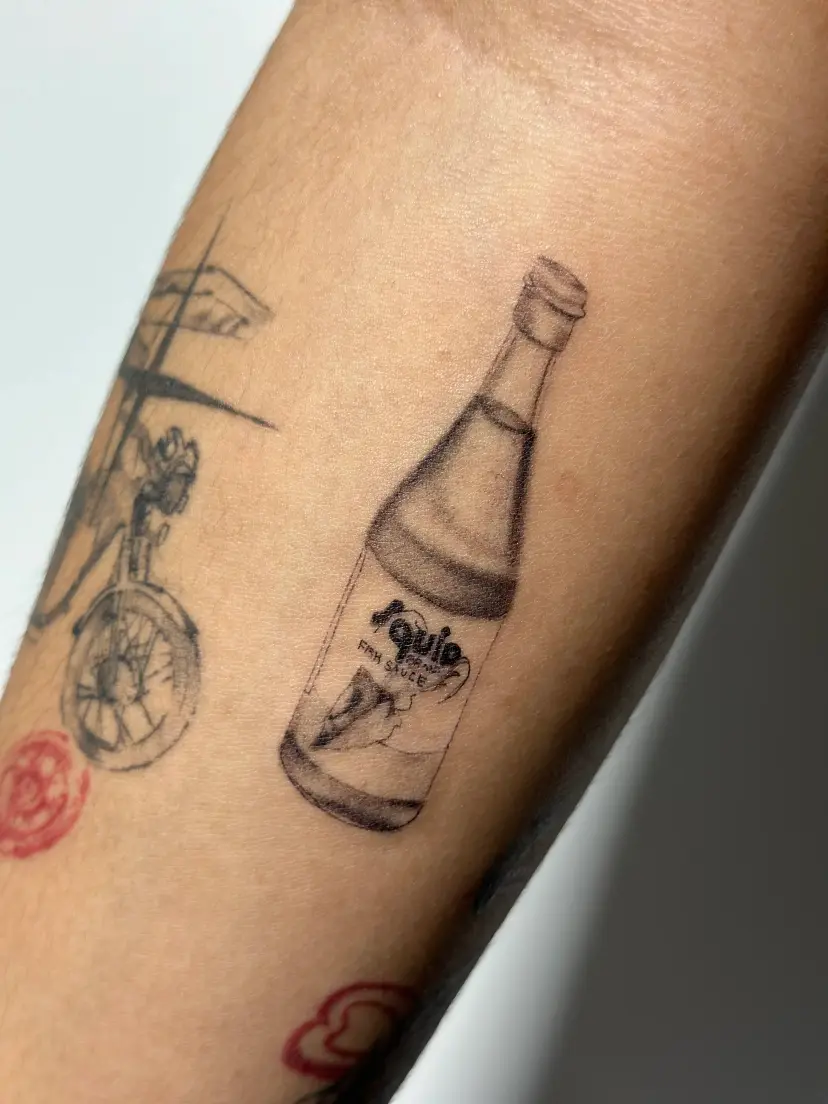 Realistic soda bottle tattoo on a forearm