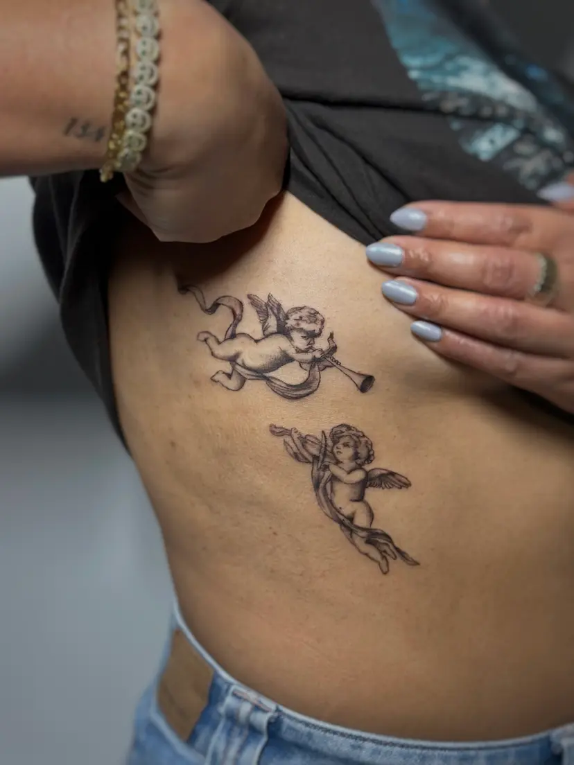 Two cherub tattoos on the ribs