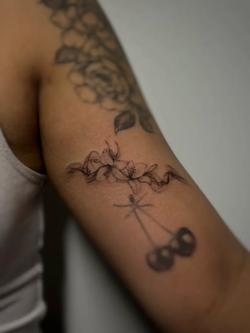 Blossom branch and cherries tattoo on an upper arm