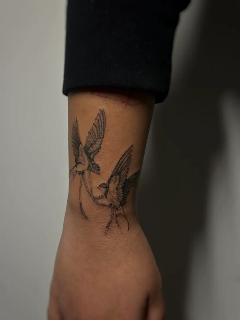 Two swallows tattoo on a forearm