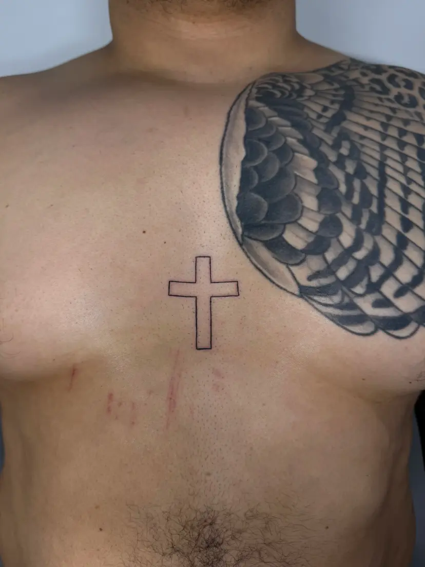 Outline cross tattoo on the chest